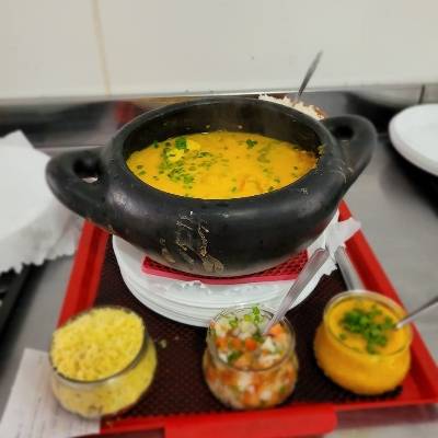 Moqueca de dourado inteira, acompanhada de pirao, vinagrete, farofa, arroz branco e batata frita.